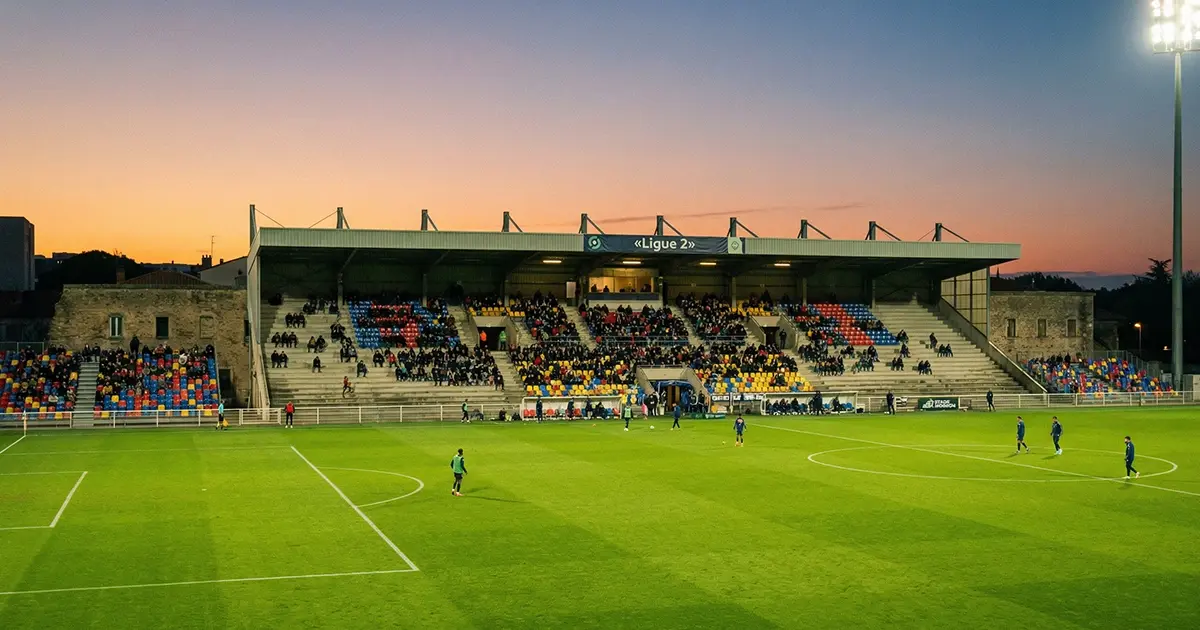 Petit stade de football français de Ligue 2 éclairé en soirée